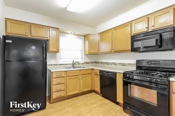 Lynwood house for rent - a kitchen with black appliances and wooden cabinets