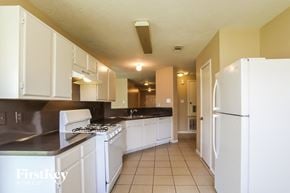 Humble house for rent - a kitchen with white appliances and white cabinets and a refrigerator