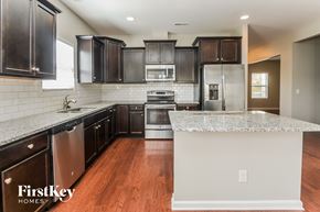 Matthews house for rent - a kitchen with granite countertops and black cabinets and stainless steel appliances