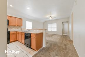 Humble house for rent - a kitchen with wood cabinets and black appliances and a carpeted floor