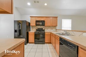 Humble house for rent - a kitchen with wood cabinets and black appliances and a sink