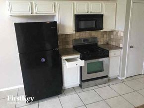 Missouri City house for rent - a kitchen with a black refrigerator and a stove