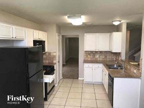Missouri City house for rent - a kitchen with white cabinets and a black refrigerator