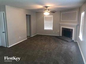 Missouri City house for rent - an empty living room with a fireplace and a ceiling fan