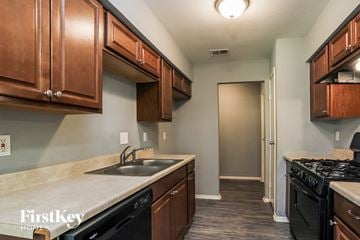 Humble house for rent - a kitchen with a sink and a stove and wooden cabinets