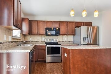 Whitsett house for rent - A kitchen with brown cabinets and a FirstKey Homes sign.
