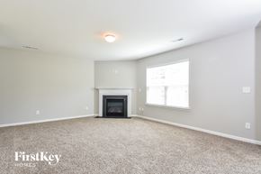 Whitsett house for rent - A spacious room with a fireplace and a window.
