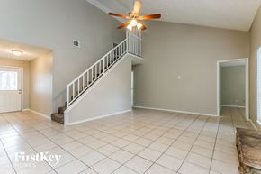 Humble house for rent - A spacious room with a staircase and a ceiling fan.