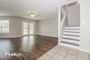 Corinth house for rent - A spacious room with wooden floors and a staircase leading to another room.