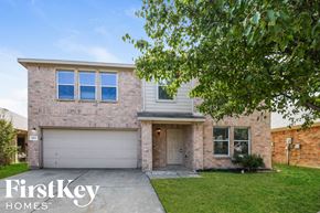 Grand Prairie house for rent - A brick house with a garage door and a tree in front.