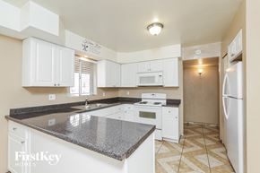 Phoenix house for rent - a kitchen with white cabinets and granite counter tops and white appliances