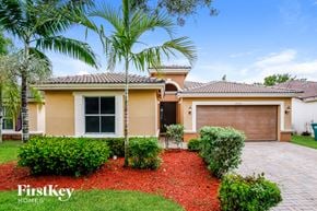 Homestead house for rent - a home with a garage and palm trees in front of it