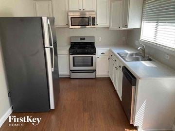 Lewisville house for rent - a small kitchen with white cabinets and stainless steel appliances