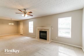 Grove City house for rent - A spacious living room with a fireplace and a ceiling fan.