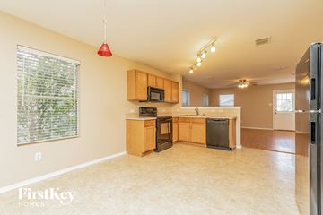 Heartland house for rent - a kitchen with wood cabinets and black appliances and a large window