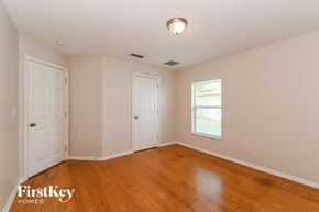 Cape Coral house for rent - a bedroom with wood floors and white walls and two doors