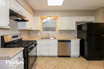 Humble house for rent - a kitchen with white cabinets and black appliances