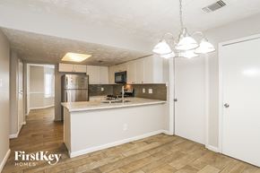 Humble house for rent - a kitchen with white cabinets and a counter top and a refrigerator