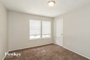 Humble house for rent - the spacious living room with carpet and a door to the bedroom