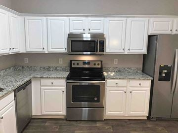 Kannapolis house for rent - A kitchen with white cabinets and a granite countertop.
