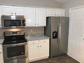 Kannapolis house for rent - A kitchen with a stove, microwave, refrigerator, and cabinets.