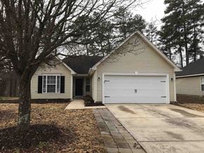 Kannapolis house for rent - A house with a white garage door is surrounded by trees.