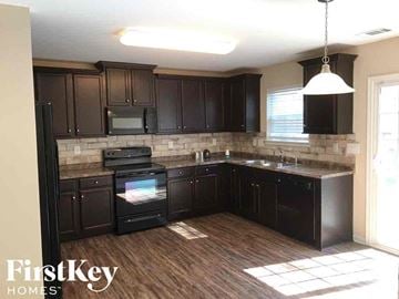 Charlotte house for rent - an updated kitchen with dark cabinets and a wood floor