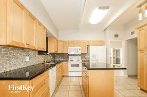 Phoenix house for rent - a kitchen with black counter tops and wooden cabinets and a white refrigerator