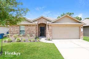 Spring house for rent - A brick house with a garage door and a sign that says "FirstKey Homes".