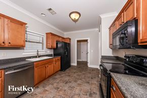 Calera house for rent - a kitchen with black appliances and wood cabinets