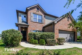 Calera house for rent - a brick house with two garage doors and a sidewalk in front of it