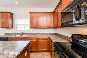 Calera house for rent - a kitchen with wood cabinets and black appliances and granite counter tops