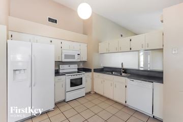 Lakeland house for rent - a kitchen with white appliances and white cabinets and tiled floors