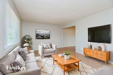 Mesa house for rent - A living room with a grey couch, a wooden coffee table, and a television mounted on the wall.