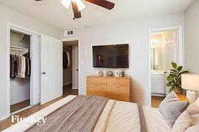 Mesa house for rent - A bedroom with a bed, a dresser, a mirror, and a television.