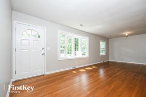 Charleston house for rent - A room with wooden floors and white walls, with a door and a window.