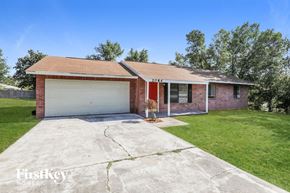Deltona house for rent - A brick house with a garage door that is open.