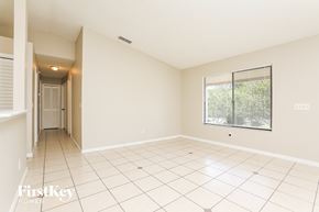 Deltona house for rent - A spacious empty room with a window and tiled floor.