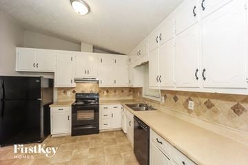 Lithonia house for rent - A kitchen with white cabinets and a black refrigerator.