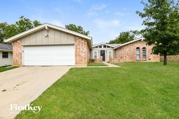 Euless house for rent - a home with a lawn and a driveway and a white garage door