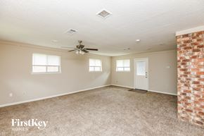Euless house for rent - an empty living room with a brick wall and a ceiling fan