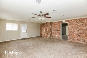 Euless house for rent - an empty living room with a ceiling fan and a brick wall