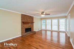 Conyers house for rent - an empty living room with a brick fireplace and a ceiling fan