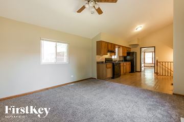Waukegan house for rent - A spacious living room with a kitchen in the background and a carpet on the floor.