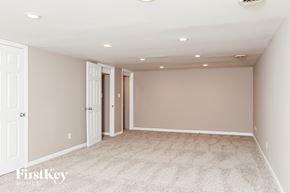 Florissant house for rent - A spacious room with carpeted floor and white walls.