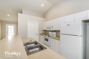 Cape Coral house for rent - a kitchen with white cabinets and white appliances and a white refrigerator