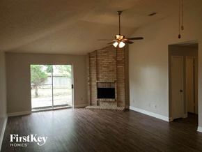 Katy house for rent - an empty living room with a fireplace and a ceiling fan