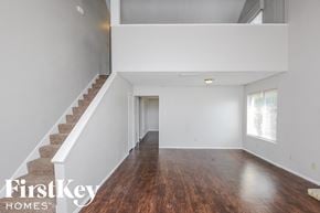 Carrollton house for rent - a living room with a staircase and white walls and wood floors