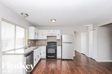 Carrollton house for rent - a kitchen with white cabinets and a refrigerator and a sink