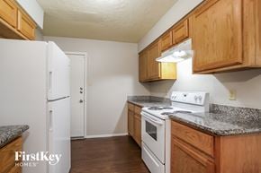 Spring house for rent - a kitchen with wood cabinets and white appliances and a refrigerator